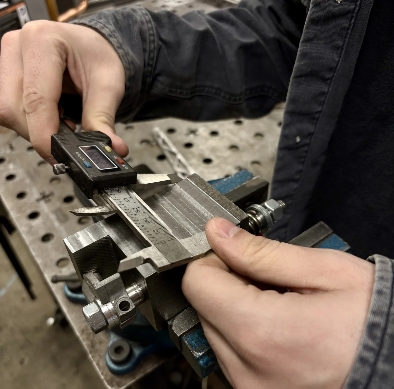 Measuring a part with a dial caliper on the workbench