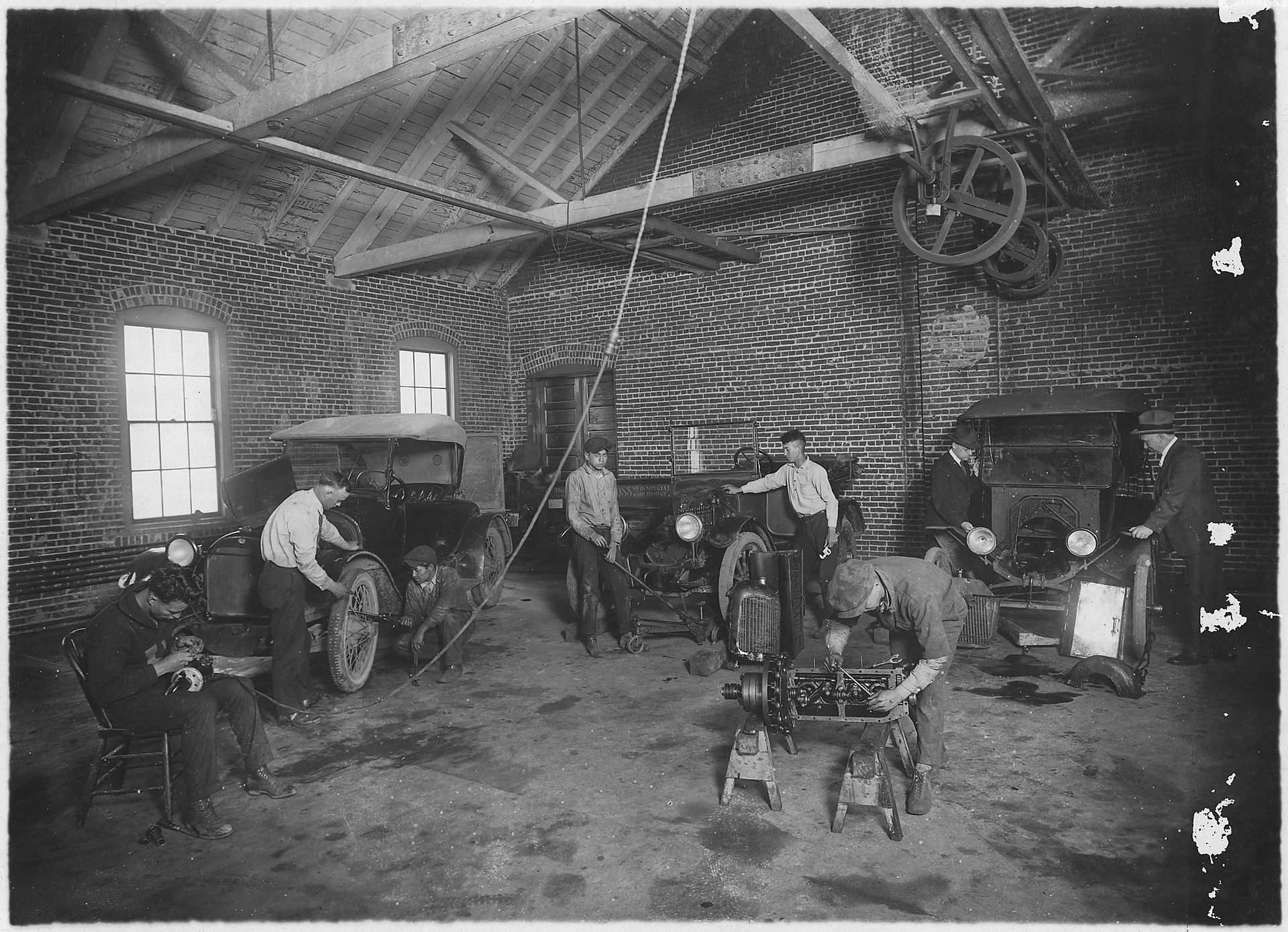 Students working on automobiles in an auto repair shop, circa early 20th century