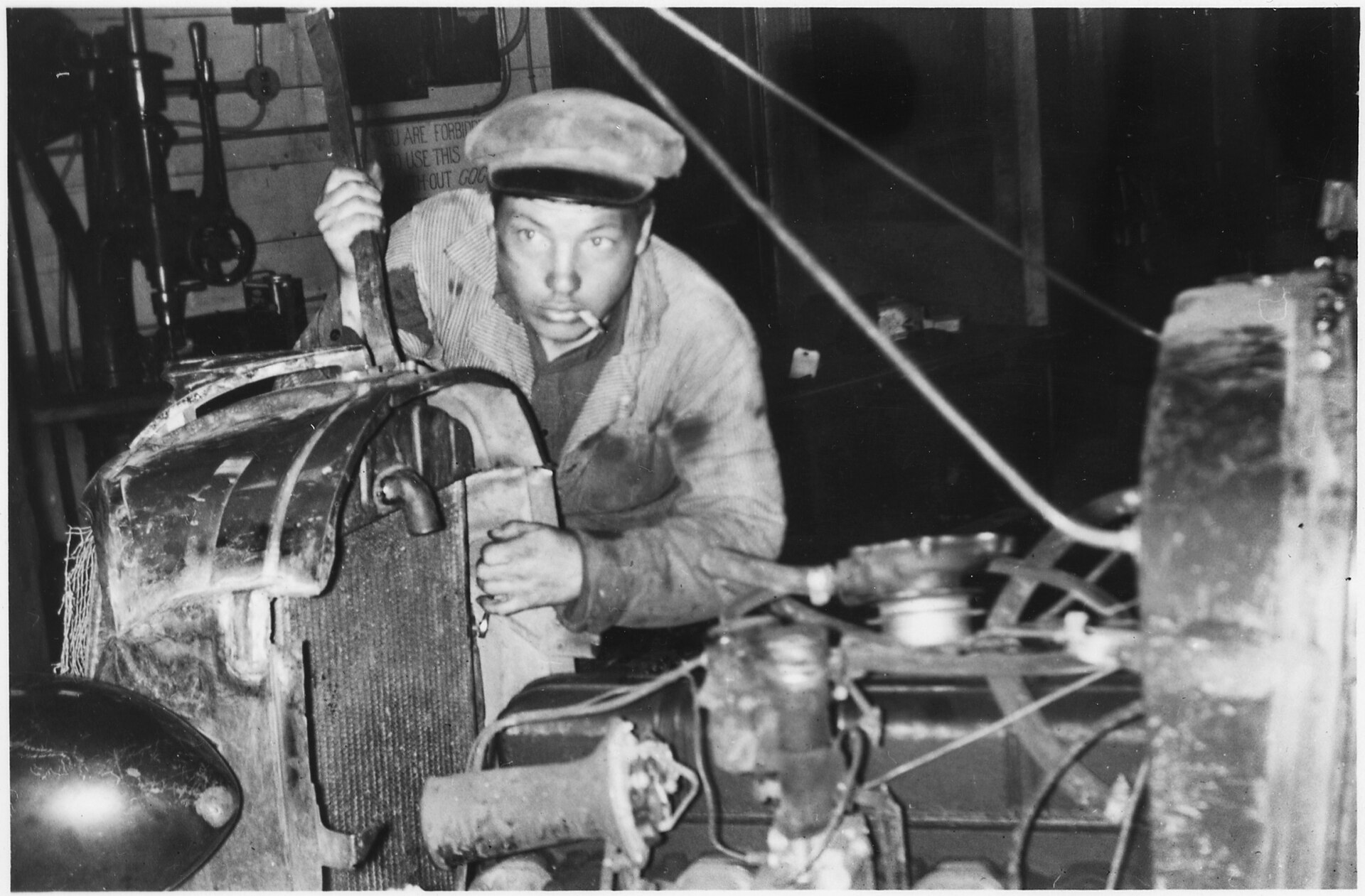 Mechanic working on an automobile in a garage, circa early 20th century